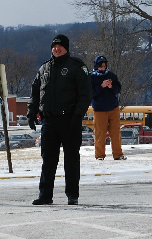 Officer Thomas Liberty stands outside as students board their buses.