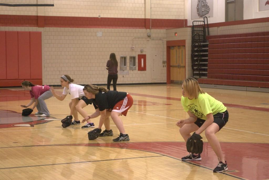 Sophomore Kristi Fiscus, Junior Carley Schroeder, Senior Hannah Mavrich and Freshman Caitlin Shaffer bend down low to catch the ball in practice on March 13.