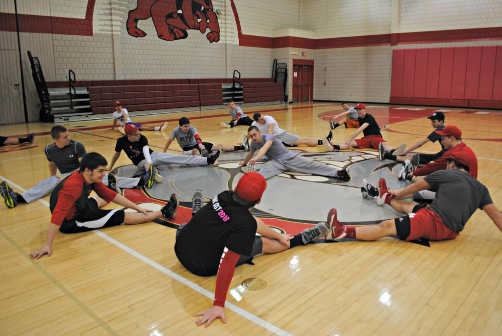 The high school baseball team stretches in a large circle in the gym before practice on March 19.