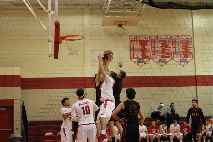 Senior Scotty Lazarus goes for a rebound against two of North Catholic’s players.