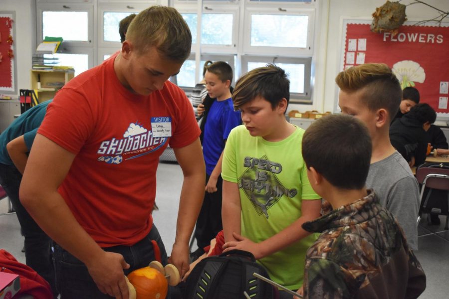 Senior Callum Heavens helps a group of middle school boys build their pumpkin  car for the pumpkin races that would follow that day.