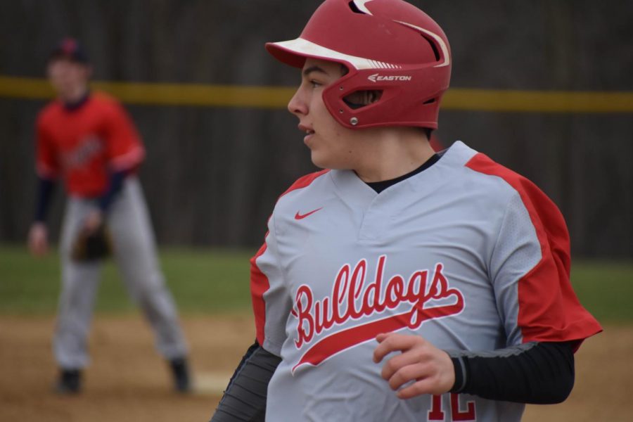 Sophomore Jacob Bauman returns to first base after scoring a hit against Summit Academy during the game on April 6.