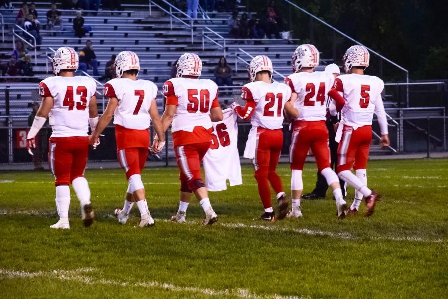 Senior football players carry Seth Weismantle’s old jersey out to to center field to honor him before the coin toss. 