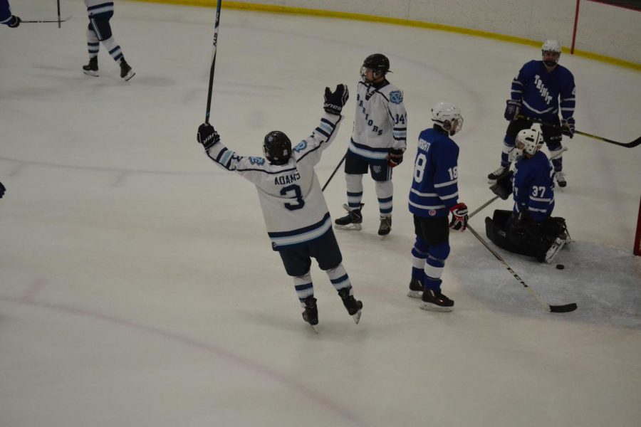 Senior Riley Adams celebrates with his arms in the air after he assists on a goal.