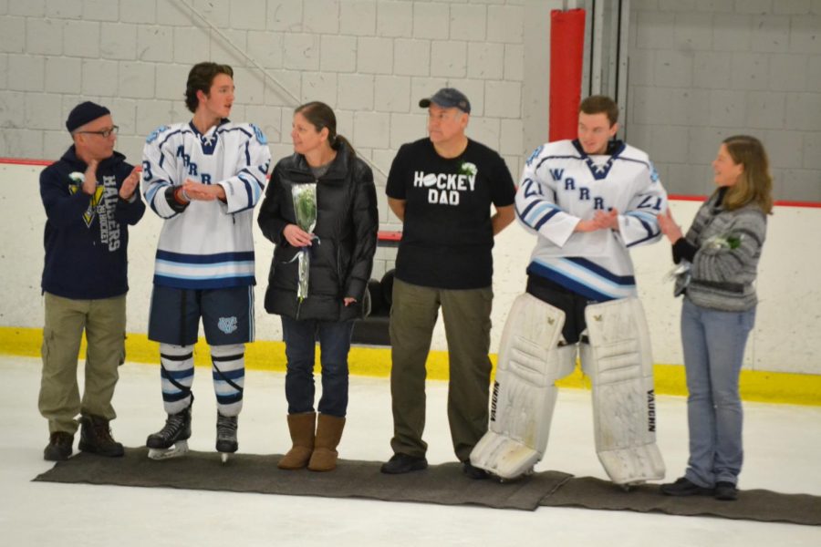 Seniors+Riley+Adams+and+Sam+Romutis+stand+in+the+middle+of+their+parents%2C+respectively%2C+for+their+commitment+as+seniors+to+the+hockey+team+at+Senior+Night+on+Feb.+14%0A