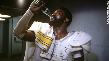 Pittsburgh Steeler’s Defensive Tackle “Mean” Joe Greene drinks a coca-cola in his famous “Hey Kid, Catch” commercial that debuted during Super Bowl XIV. 