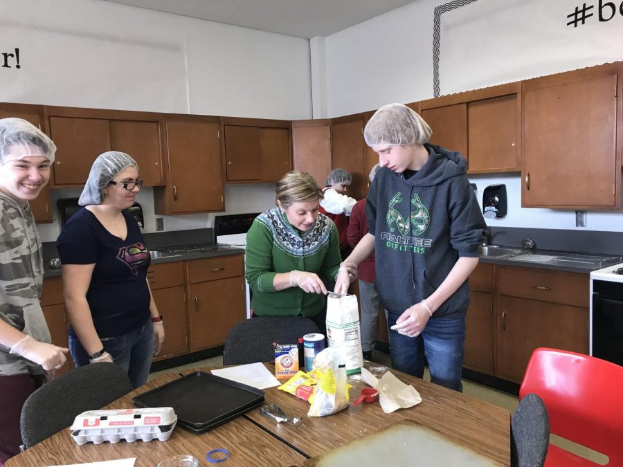 April English assists freshman John Nelson with measuring flour as sophomore Micha
Henley works with another student behind them to make pastries for Cafe 116.