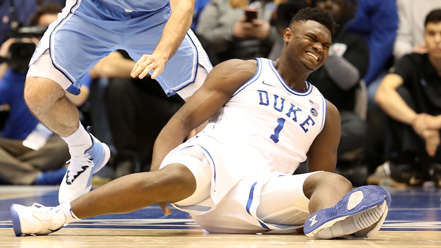 Duke freshman Zion Williamson grimaces in pain as he lies on the court, moments
after his shoe split against North Carolina on Feb. 20.