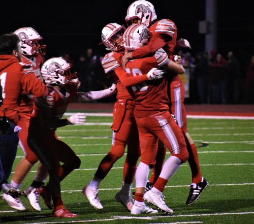 Teammates hug and lift Garrett Paxton moments after he made the game-winning field goal to keep the teams undefeated season alive and defeat their rival New Brighton.