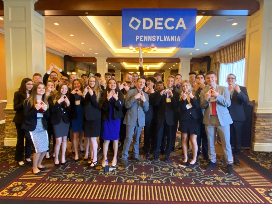 Deca members stand inside Hershey Lodges lobby and pose for a photo.