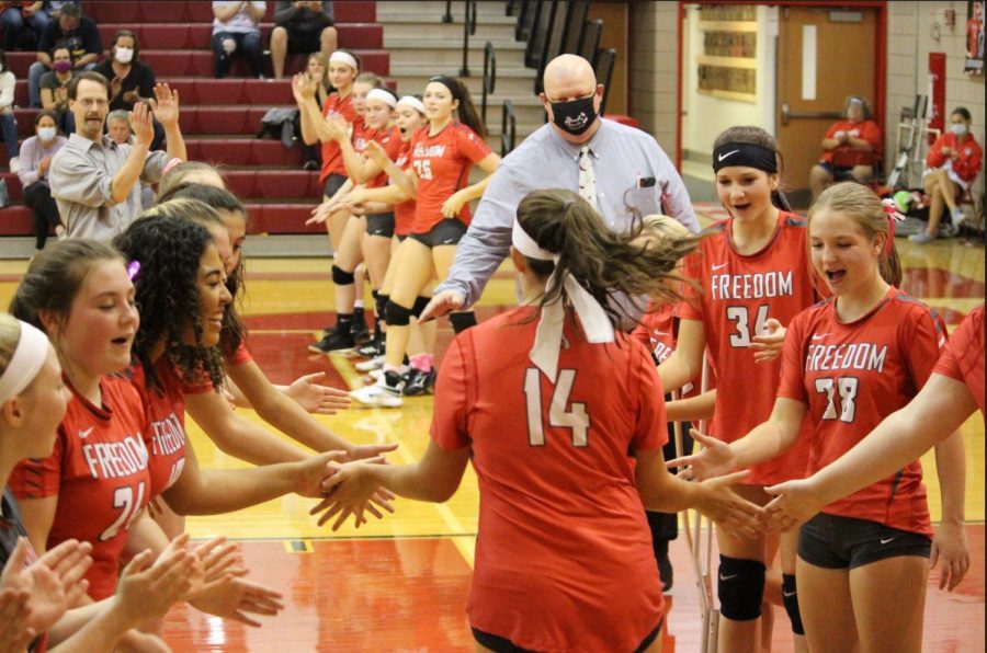 Junior Olivia Evans gives her teammates high fives as she prepares herself for the last game of the season against New Brighton. 