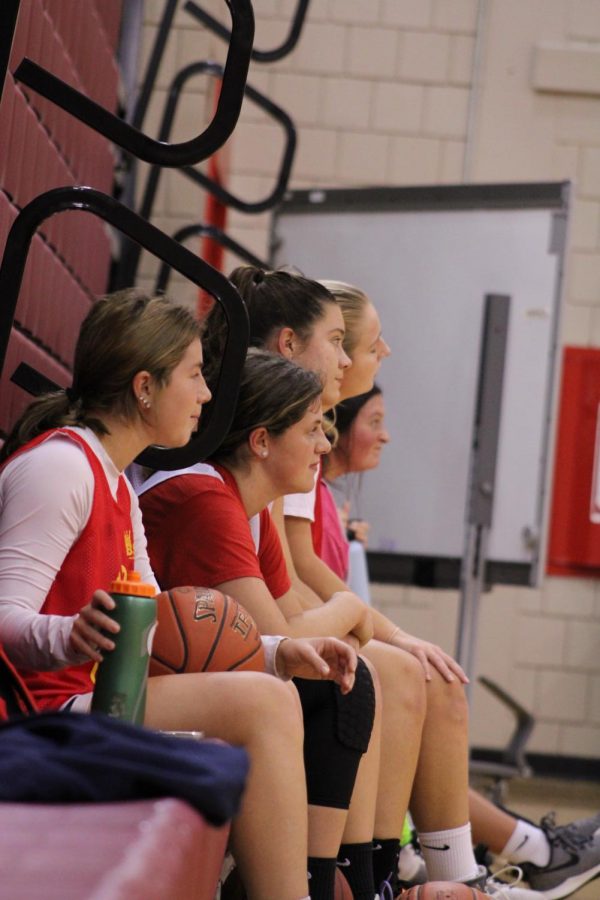 The team sits on the sideline to take a drink of water and listen to their coaches before going back to practicing. 