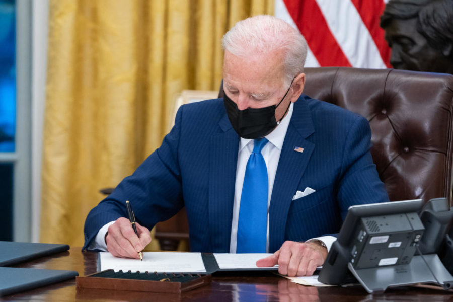 President Joe Biden signs executive orders on immigration Tuesday, Feb. 2, 2021, in the Oval Office of the White House. 