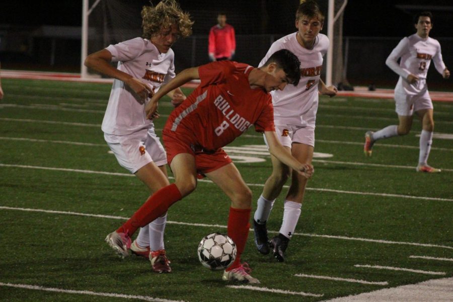 Sophomore Dylan Scheel protects the ball from the North Catholic Trojans on Oct. 7. Scheel is one of many student athletes who has faced difficulties getting the necessary credits required by the NCAA. 