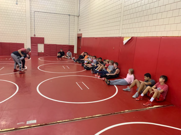 The varsity and junior high teams watch as their coach shows them a technique with junior Trenton McCray.