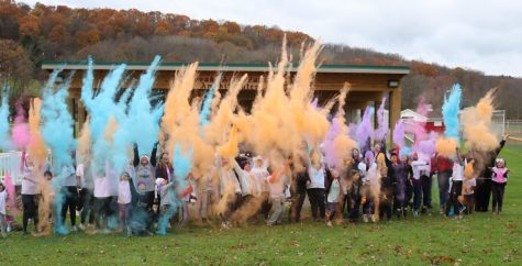 Drama Club members alongside Color Run participants cheerfully toss colored chalk in the air in celebration after a successful
fundraiser.