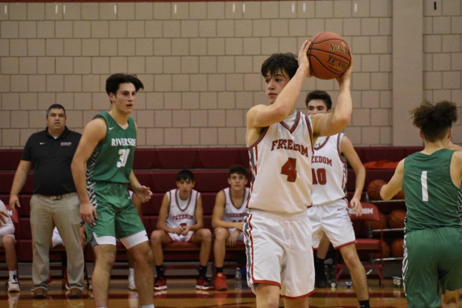 Senior Max Bozza holds the basketball over his left shoulder as he looks for a teammate to pass the ball to during a game against the Riverside Panthers on Dec. 14, 2021.