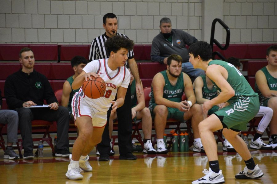 Dribbling the ball, junior Silas McCullough moves towards the Panthers side of the court to score during a home game on Dec. 14. 