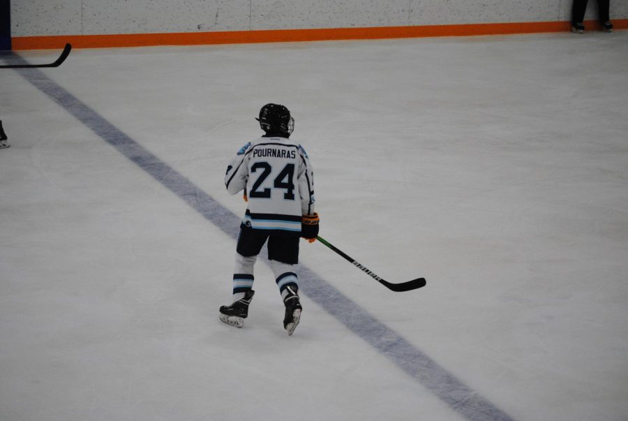 Looking+for+the+hockey+puck%2C+sophomore+Aiden+Pournaras+gets+ready+to+skate+towards+his+teammates+and+opponents.