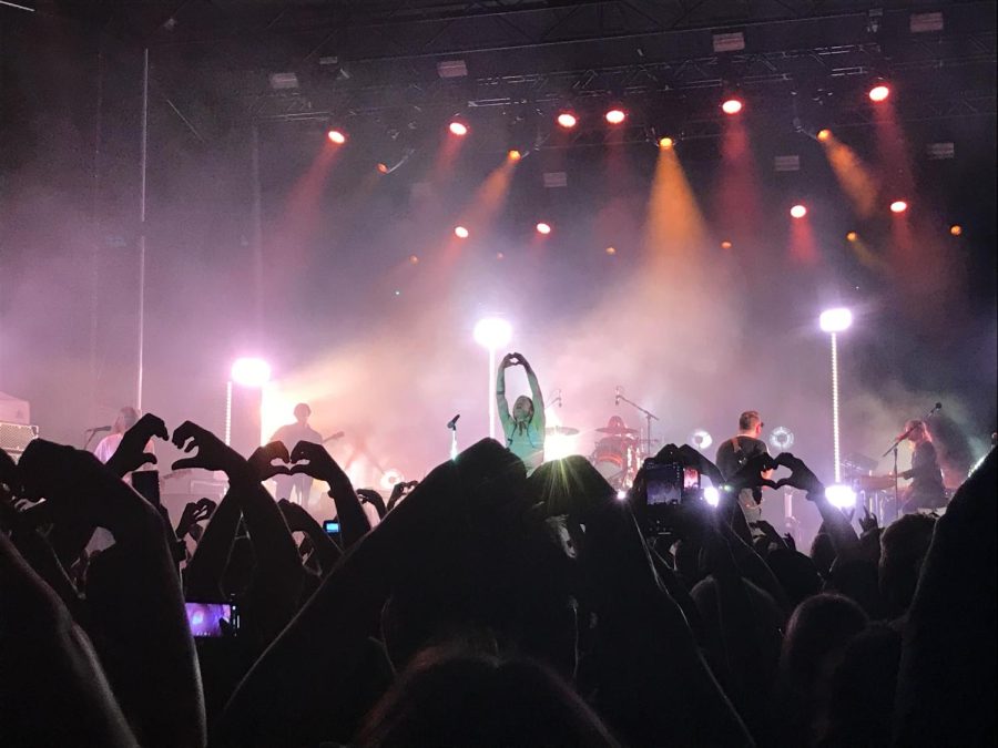 Holding their hands in the air, fans make a heart shape to show their affection for Cage the Elephant. Fans are known for creating a loving environment during concerts, especially when they are allowed to enjoy what they love.