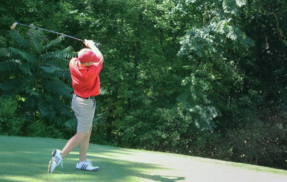 At a home game against Rochester at Rollng Acres on Aug. 22. Sophomore Richard Horgos delivers a quick swing to his golf ball, causing the surroundiwng grass and dirt to spray forward.