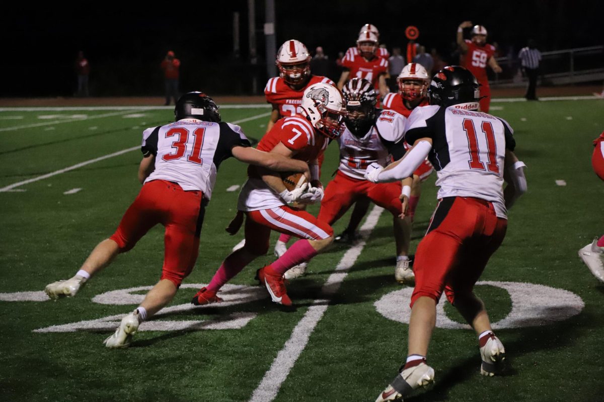  Breaking blocks: Senior Cody Patterson pushes his way through the Mohawk defense on Oct. 13. “It feels amazing. When the offense does their job and clears the way for a touchdown, there is nothing better than hearing the fans scream behind you,” Patterson said. All of the players wore pink socks to support their community during the annual “Pink Out” game to support breast cancer awareness.
