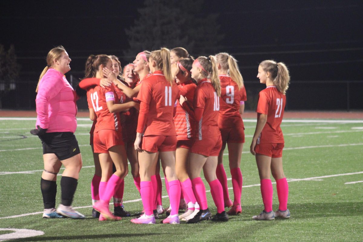 Kickin' it: The girl’s soccer team embraces Senior Emma Falk during her time on the field for senior night despite her injury. The soccer team started all of their seniors on the field for the start of the game.
