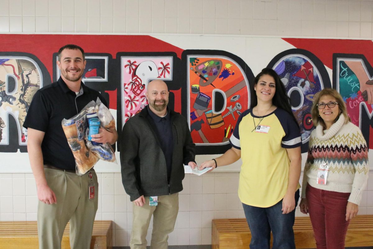 Paying it forward: After raising over $1,600, Katie Prest hands a check to members of Freedom's administration. Prest raised money to pay off student lunch debt. Left to right: High school principal, Mr. Steven Mott, Director of Food Service, Mr. Randy Walker, Prest and superintendent, Ms. Diane Workman