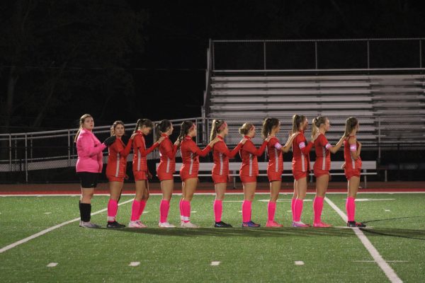 Girl Power: Standing in unison, the girls soccer team stares at the flag as the national anthem is played. The team saw extreme success this season, helping to put more awareness on girls sports.