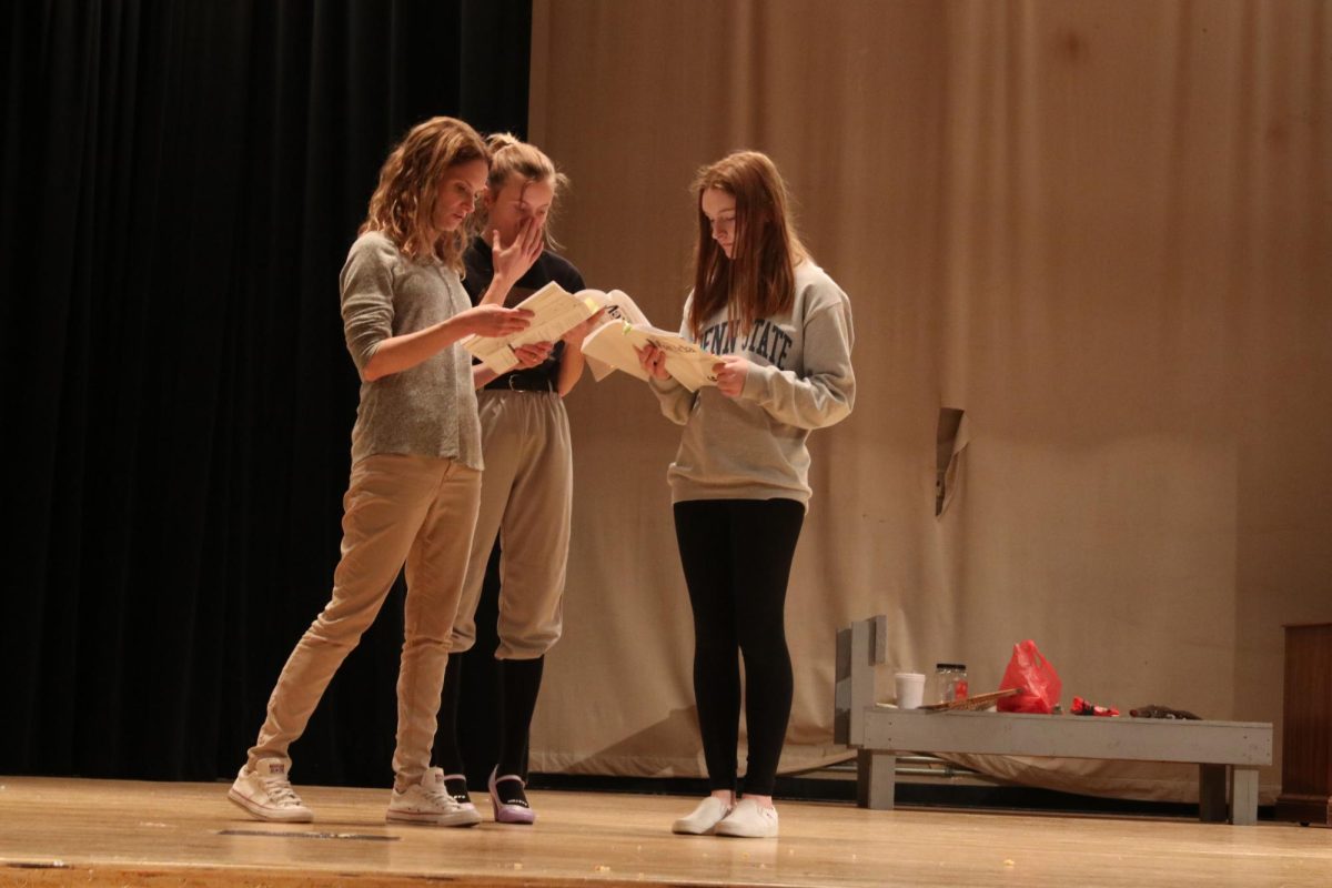 From the top: Preparing to enact a scene, senior Morgan Shaffer (center) and junior Lainey Tuszynski (right) review their lines alongside Ms. Heather Giammaria (left). Lead members spend a lot of time practicing and memorizing their lines to flawlessly perform when the curtains open.