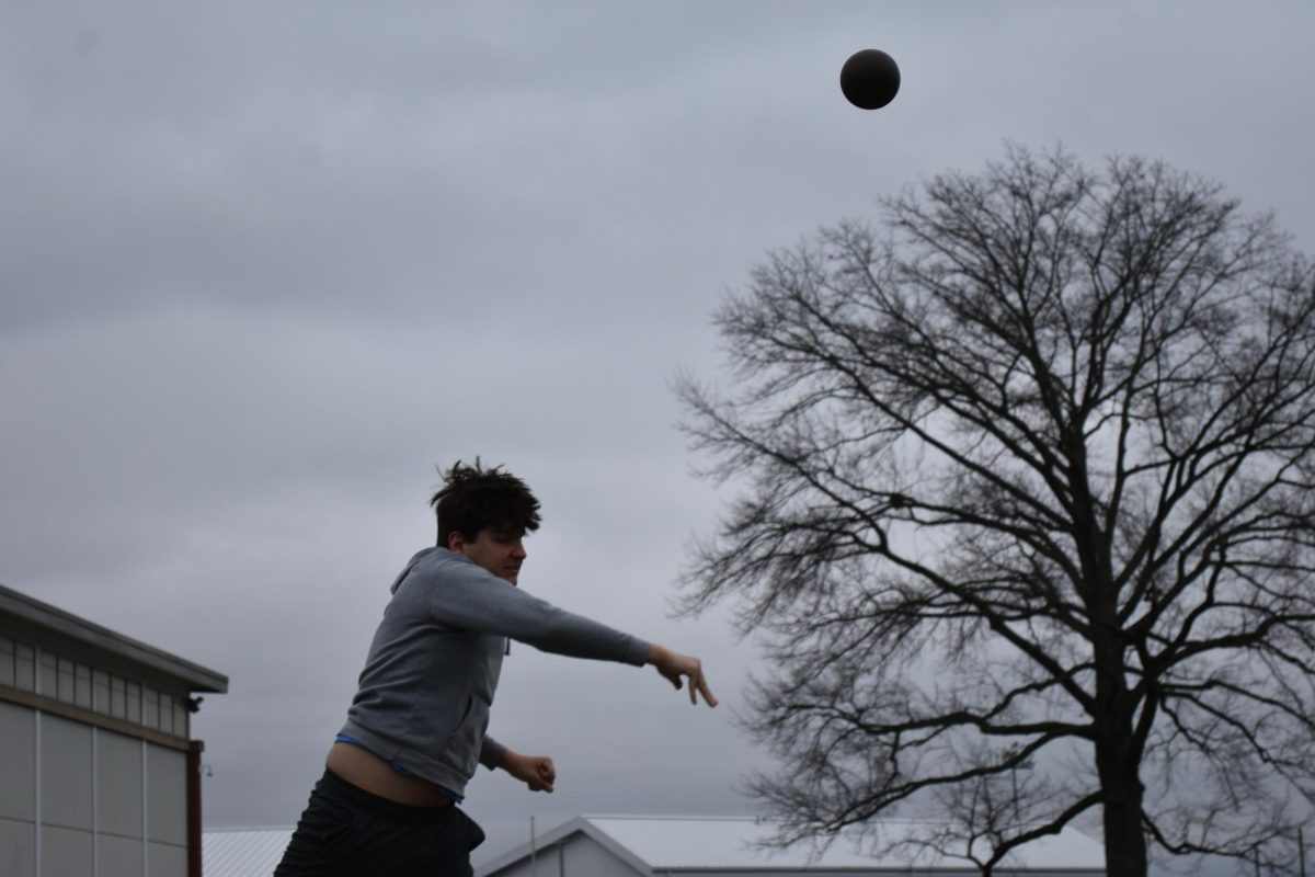 Hard toss: Swinging his arm, Christopher Denkovich launches the shot at track practice on March 14. Students divide into smaller groups based on their discipline for better focus on improving their skills.