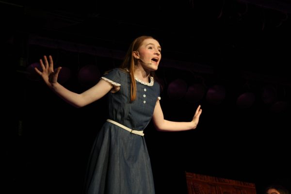Chokey chant: Stretching her arms out, junior Lainey Tuszynski, playing Matilda, exclaims a story to the audience on the opening night of the musical. During this scene, Tuszynski is interacting with Vera Armenio, who played the librarian.