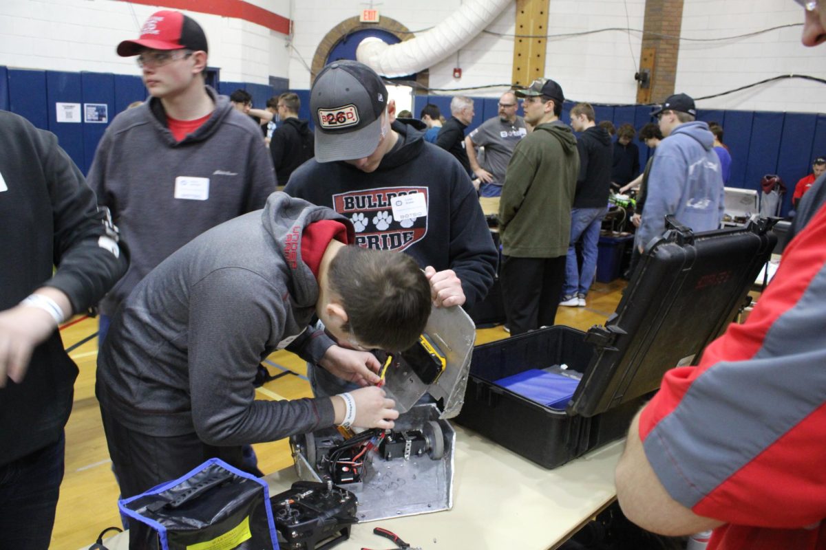 Making alterations to the robot, Lucas Bradel holds the robot while Paul Ribellia connects the wires. Making sure all of the wires are connected is a vital part in ensuring the robot maneuvers well during battle.
