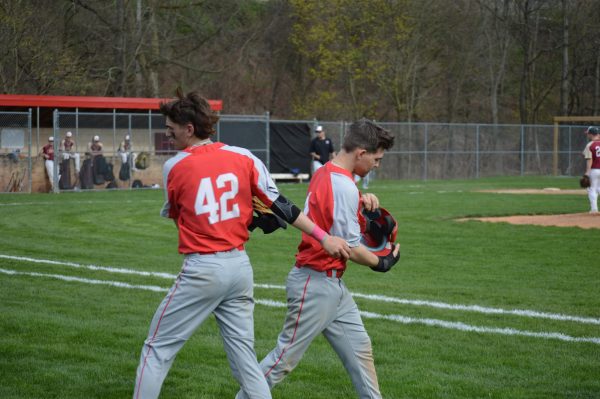 Passing off: Switching places on the field, junior Thomas Ward and senior Tyler Schultheis, pass equipment to each other. Since Ward is the only catcher, he often needs a baserunner, which gives Ward time to get ready for the next inning. 