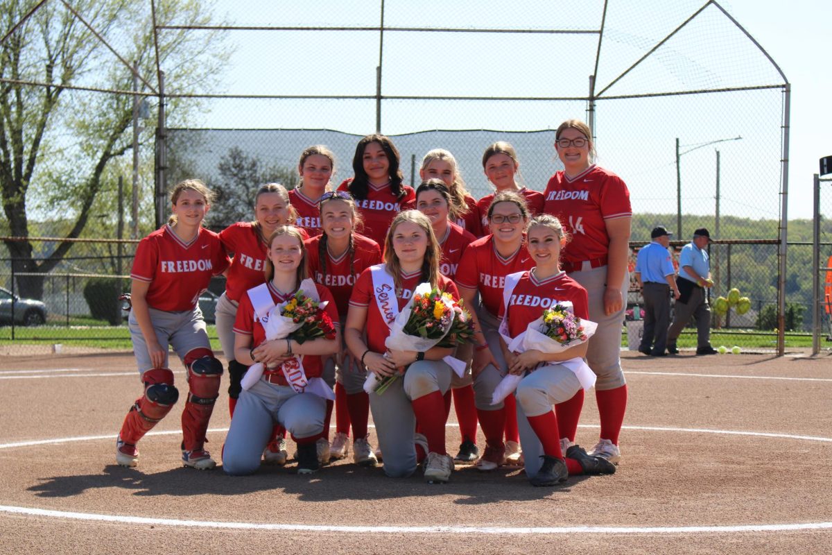 Smiling proudly: Holding flowers, the softball team poses for a picture before their last home game against Aliquippa on April 28. This game would be the girls’ second win.