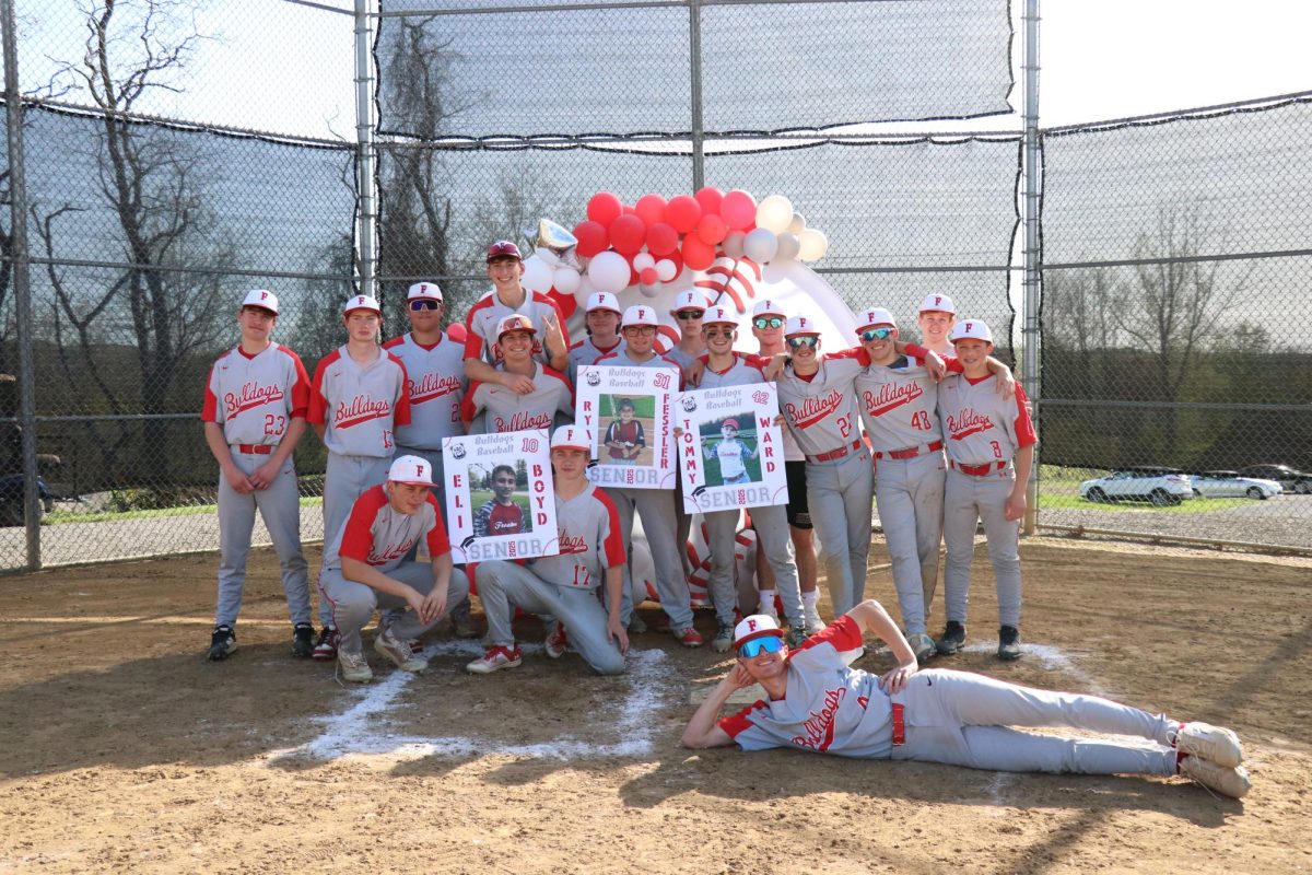Team effort: Smiling, the baseball team honors their seniors during a post-game ceremony. During the ceremony, there were decorations set up and signs made for the seniors to hold.
