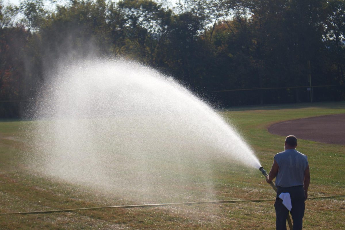 One drop at a time: Dayne Bailey, maintenance, waters the newly finished outfield to ensure the sod roots properly. Due to the lack of rain, the sod has to be watered manually every day.
