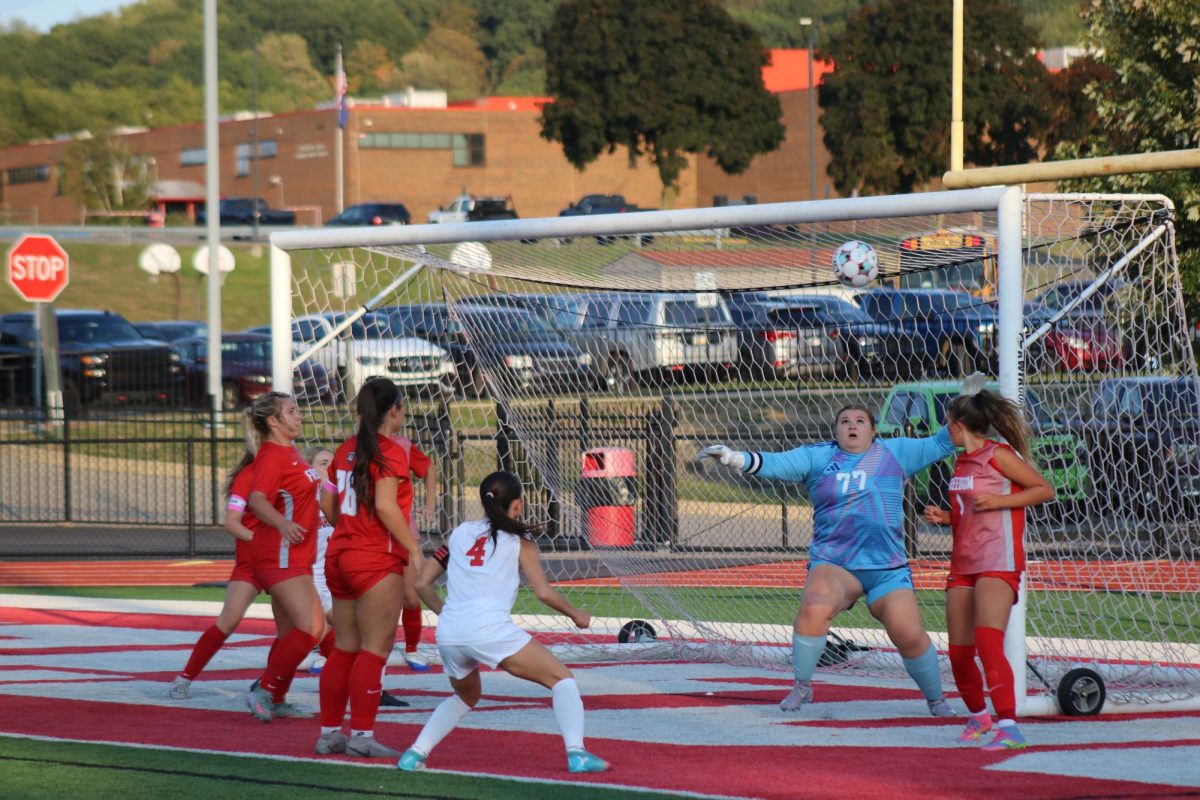 Eyes on the ball: Looking up at the soccer ball, goalie Trinity Vojtko (12) attempts to catch the ball so the other team cannot hold on to it. Vojtko communicates with her teammates so they know when to let her catch the ball, or to kick it out of their end.