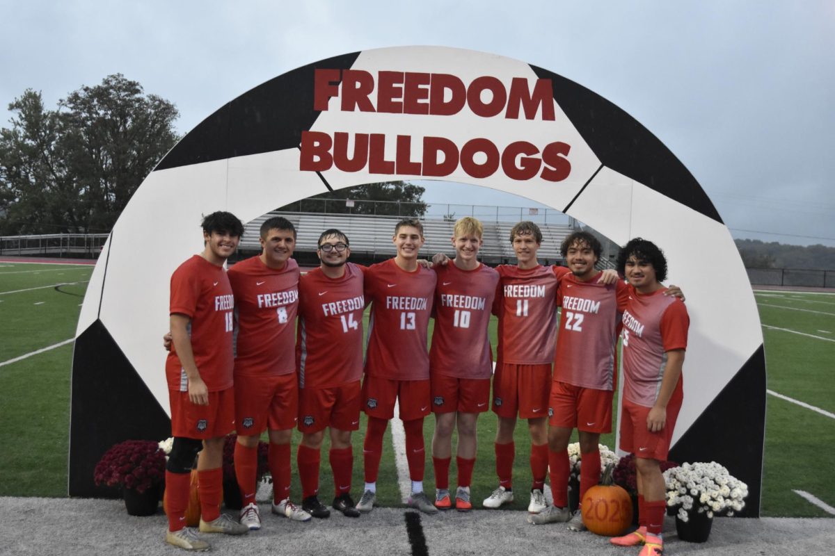 Farewell footwork: Seniors stand together under the archway, through which they walked to be celebrated. Before the game, each senior and their  families walked along with them as an announcer talked about the achievements and plans of the seniors.
