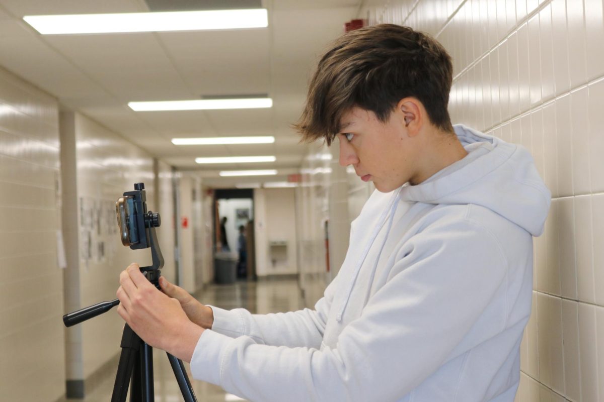Film ready: Troy Reynolds (11) carefully adjusts the tripod so his phone camera captures the subject. For the Pennsylvania Scholastic Press Association regional competition, Reynolds submitted a video package.