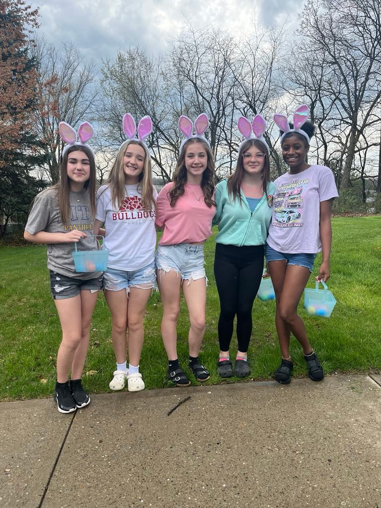 Buckets of joy: Just before scattering eggs throughout a yard, cheerleaders take a picture together sporting baskets and their bunny ears.
